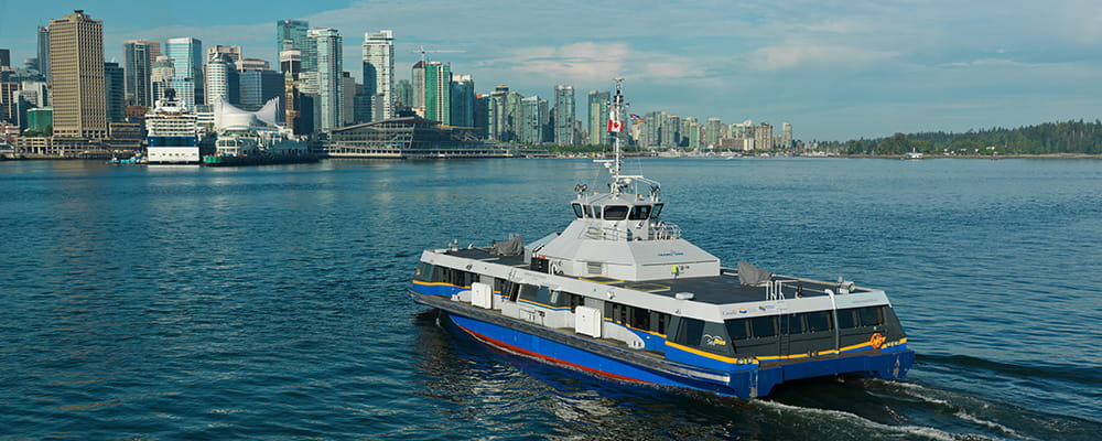 A SeaBus sailing towards downtown Vancouver on a cloudy day